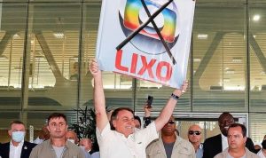 Bolsonaro segurando uma placa de "Globo lixo". Imagem/Reprodução: Youtube